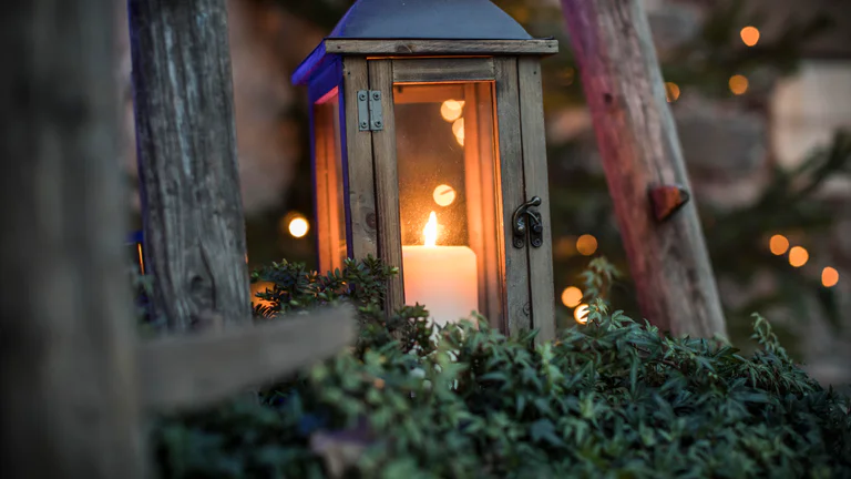Eine Laterne aus Holz und Glas mit einer leuchtenden Kerze darin.