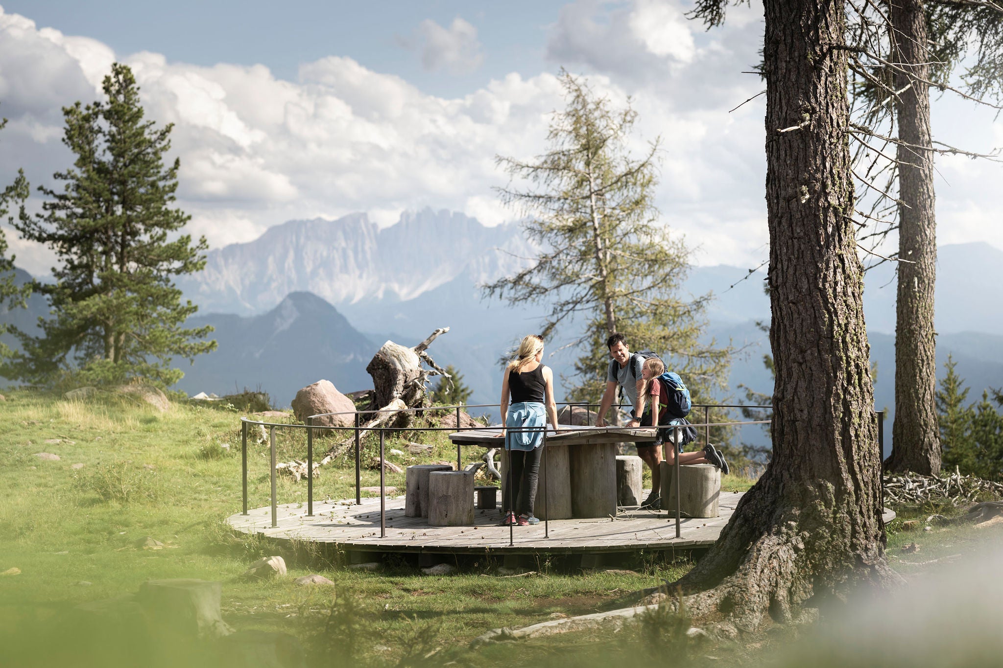Eine junge Familie verweilt beim Wandern an einer Aussichtsplattform auf dem Ritten und genießt das Dolomitenpanorama.
