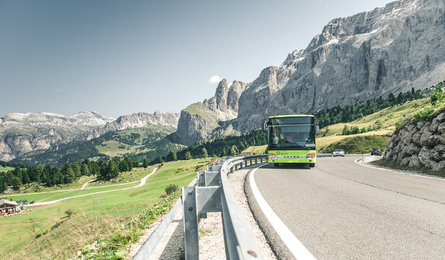Ein Bus fährt einen Dolomitenpass inmitten des beeindruckenden Bergpanoramas hinauf.