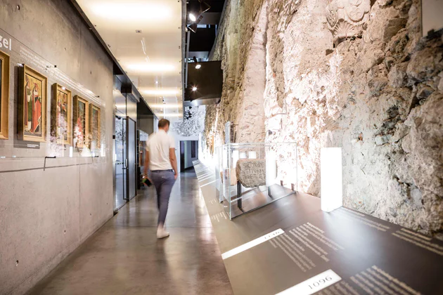 Un uomo cammina in un museo in Alto Adige con muri di pietra a vista