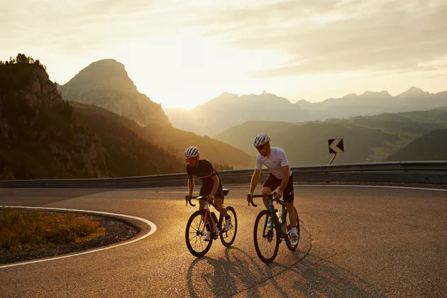 Due persone con bicicletta da corsa su un passo dolomitico al tramonto