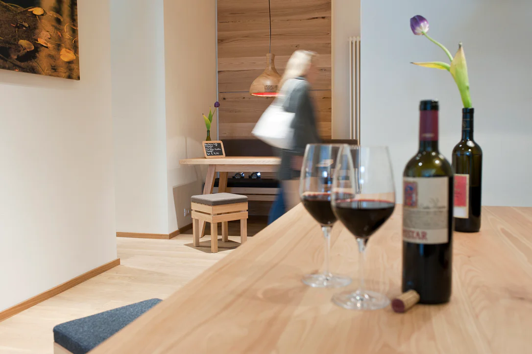 Due bottiglie e due calici di vino rosso adagati su un tavolo in un ambiente moderno