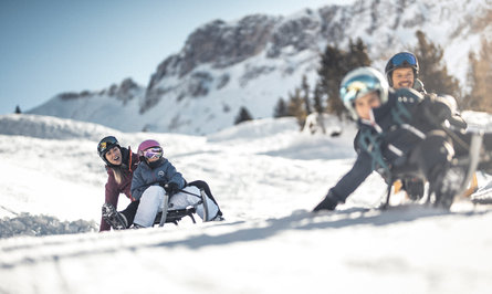 Una famiglia con bambini si diverte slittando sulla neve