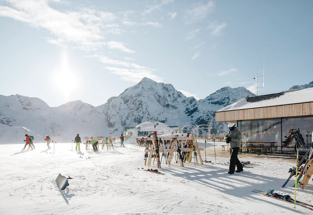 Skihütte im Schnee, mit mehreren Skifahrern vor der Hütte