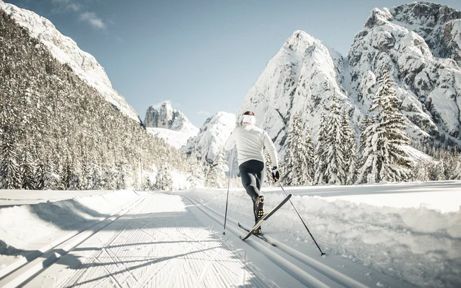Een persoon langlauft door met sneeuw bedekte bergen