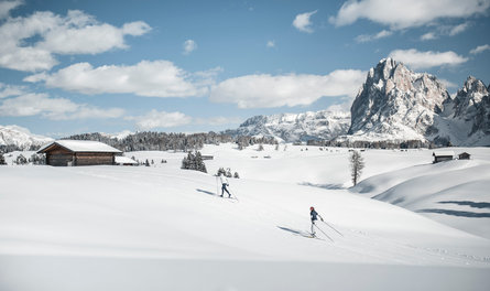 Blick auf eine verschneite Alm in Südtirol mit Hütten und Gebirge im Hintergrund