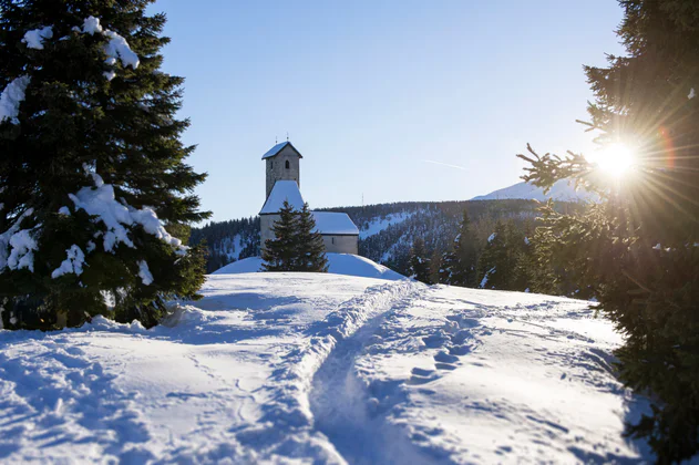 Schneebedeckte Kirche zwischen verschneiter Landschaft