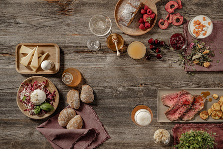 Południowotyrolskie produkty podane na stole, w tym ser, miód, dzikie zioła i mięso. 