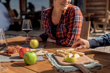 Een vrouw en een man genieten van Zuid-Tiroolse specialiteiten zoals appels, kaas en wijn.