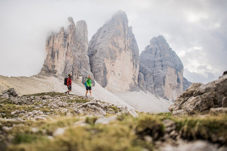 Due persone fanno un'escursione a piedi sotto le vette delle Tre Cime 