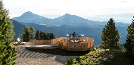 Punto panoramico di osservazione in Val d'Ega. Un uomo osserva la struttura metallica sulla quale è presente una cartina a 360 gradi del panorama circostante.