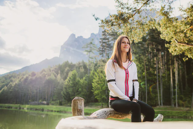 Una spensierata ragazza seduta sulle sponde del laghetto di Fiè con lo Sciliar sullo sfondo