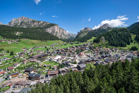 Panoramic view over Sëlva/Selva sorrounded by green fields, forests and majestic mountains in the Dolomites region Val Gardena