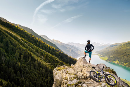 Ein Mann mit dem Rad blickt über den Reschensee im Vinschgau