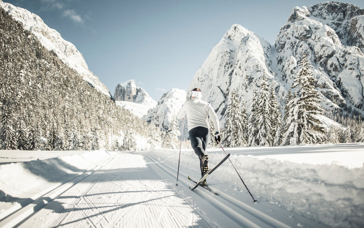 Ein Mann beim Langlaufen in einem verschneiten Dolomitental. unterweg.s