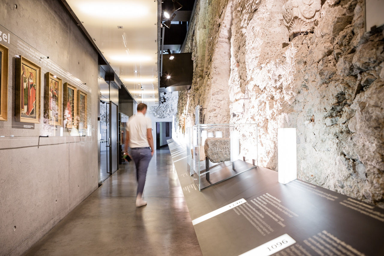 Ein Mann geht an alten Mauer entlang durch eine Ausstellung im Kloster Marienberg.