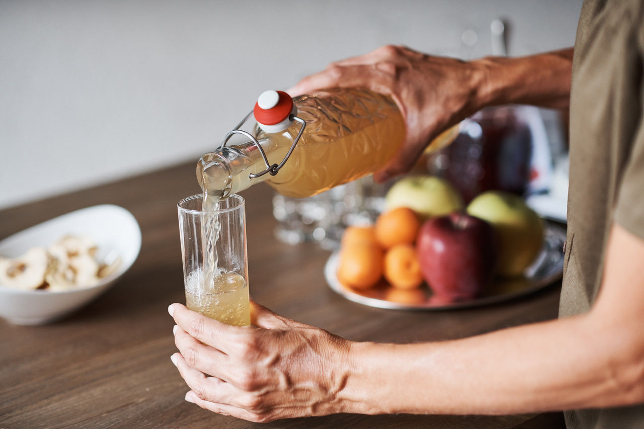 Eine Person gießt sich Apfelsaft in ein Glas