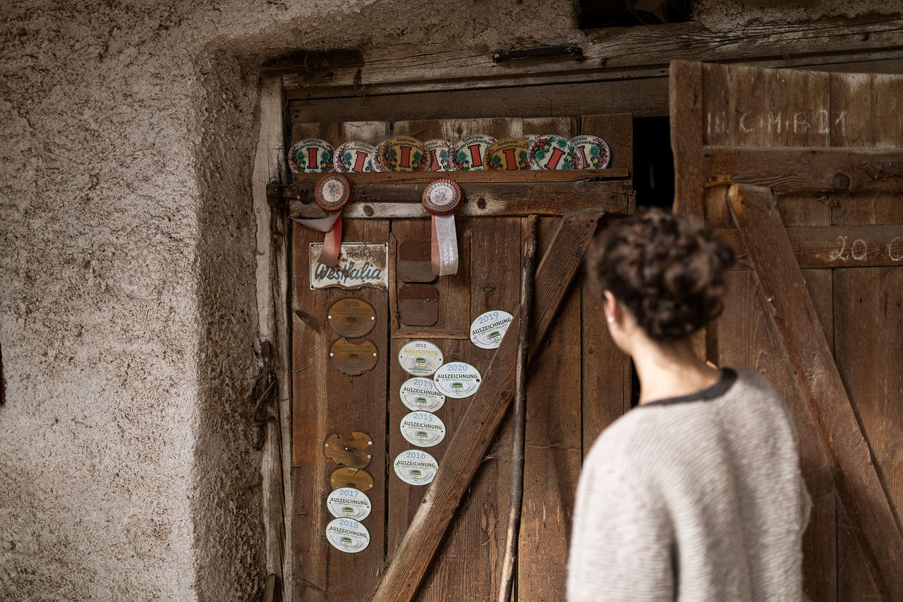 Anna Pfeifer steht vor einer alten Holztür mit mehreren Auszeichnungen