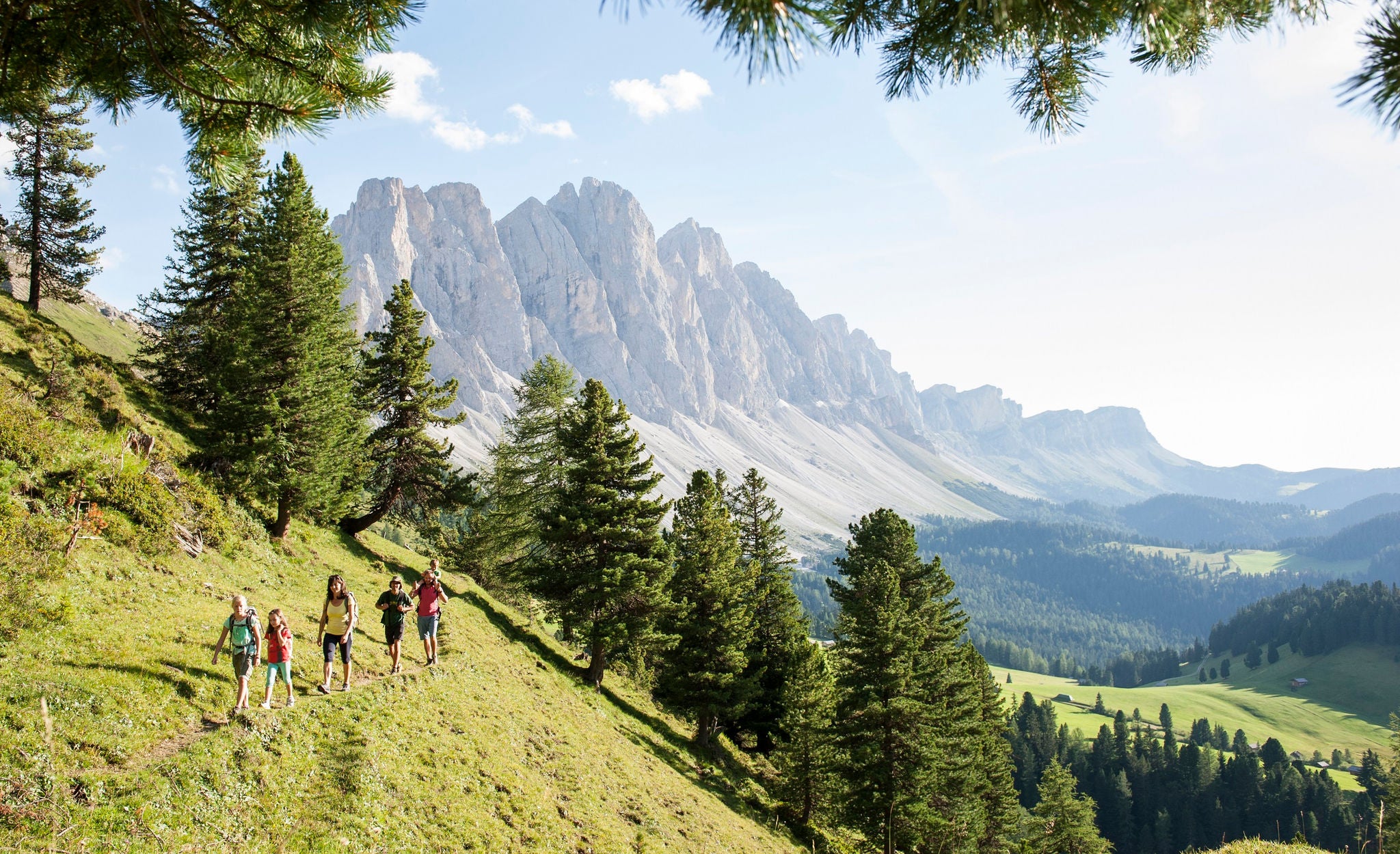 Mehrere Personen wandern auf einem schmalen Fußpfad durch die Bergwelt der Villnösser Geisler.