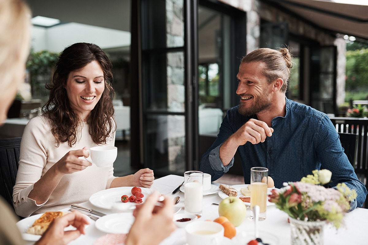 Drei Freunde sitzen sitzen beim Frühstück auf einer Terasse