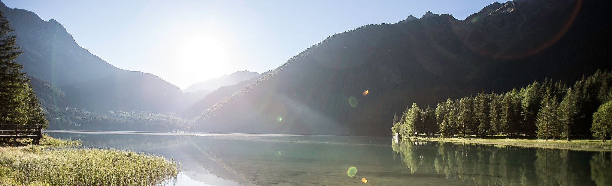 Die Sonne spiegelt sich im Wasser des Antholzer Sees.