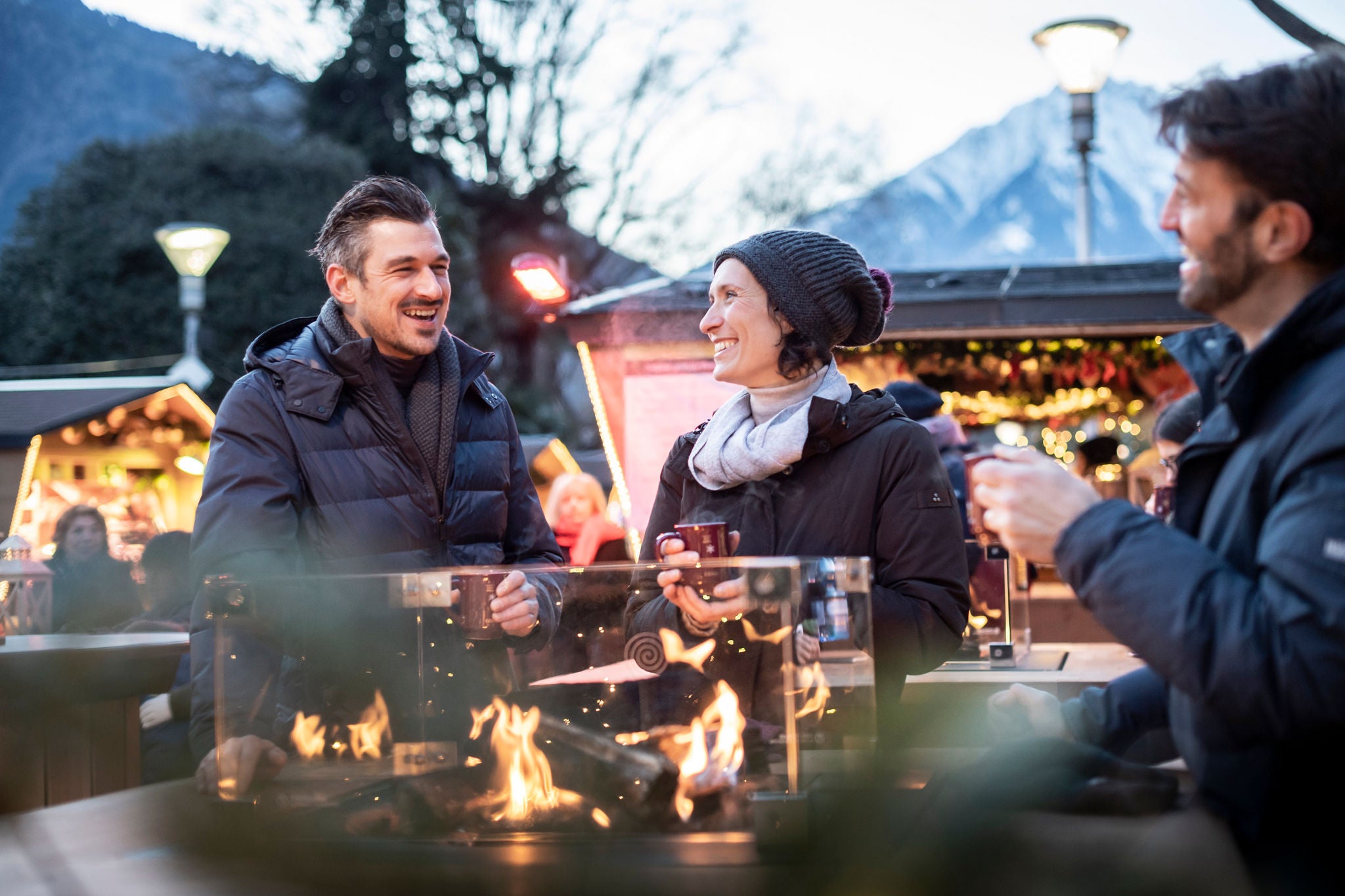 Zwei Männer und eine Frau mit einem Heißgetränk aufdem Christkindlmarkt in Meran.