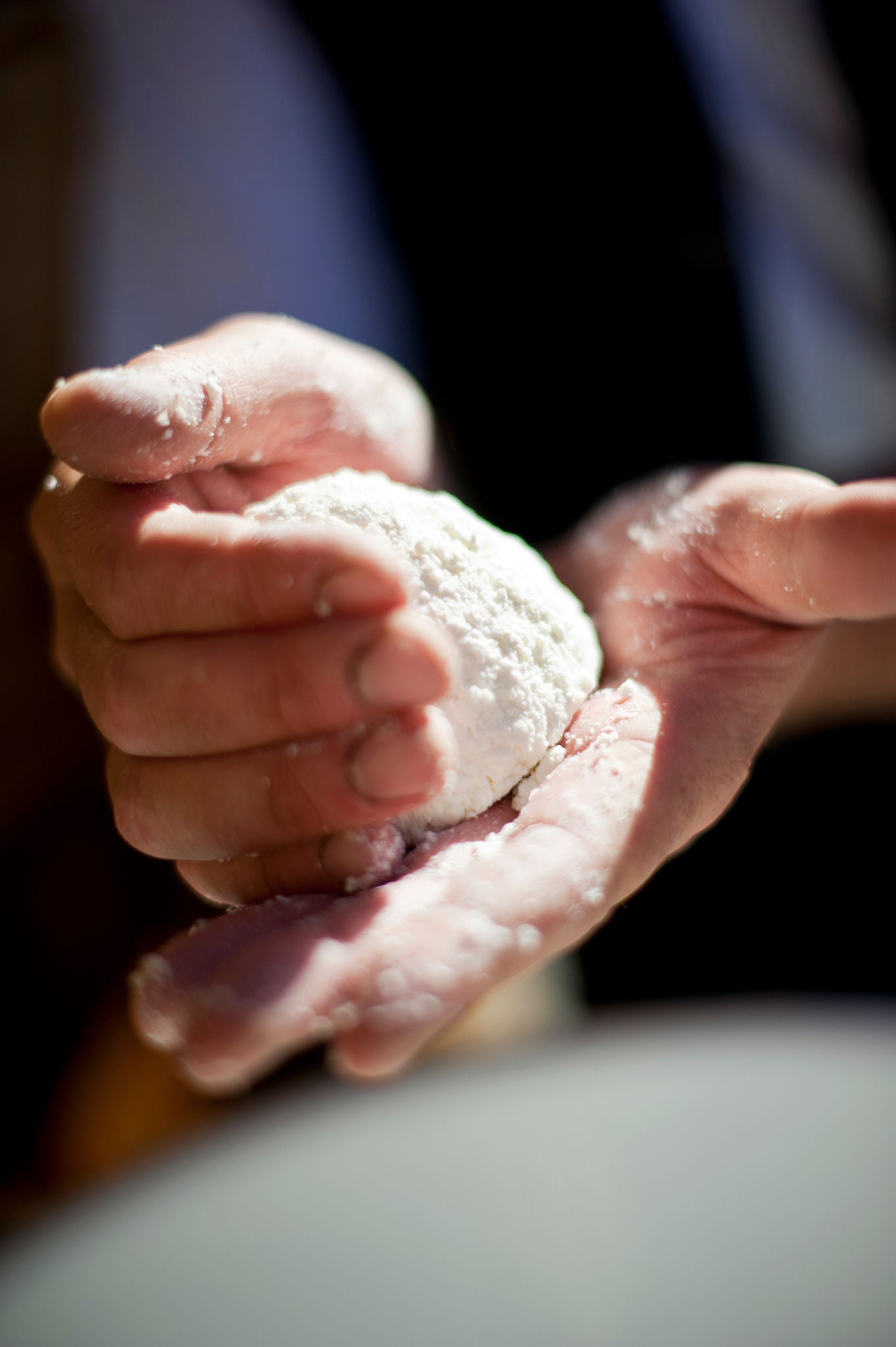 Eine Person hält ein Stück Ziegenkäse in der Hand