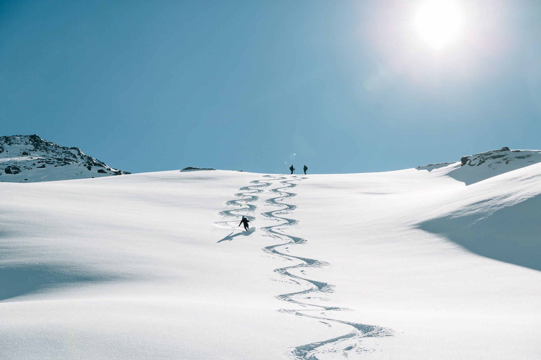 Person bei Tiefschneeabfahrt bei sonnigem Wetter