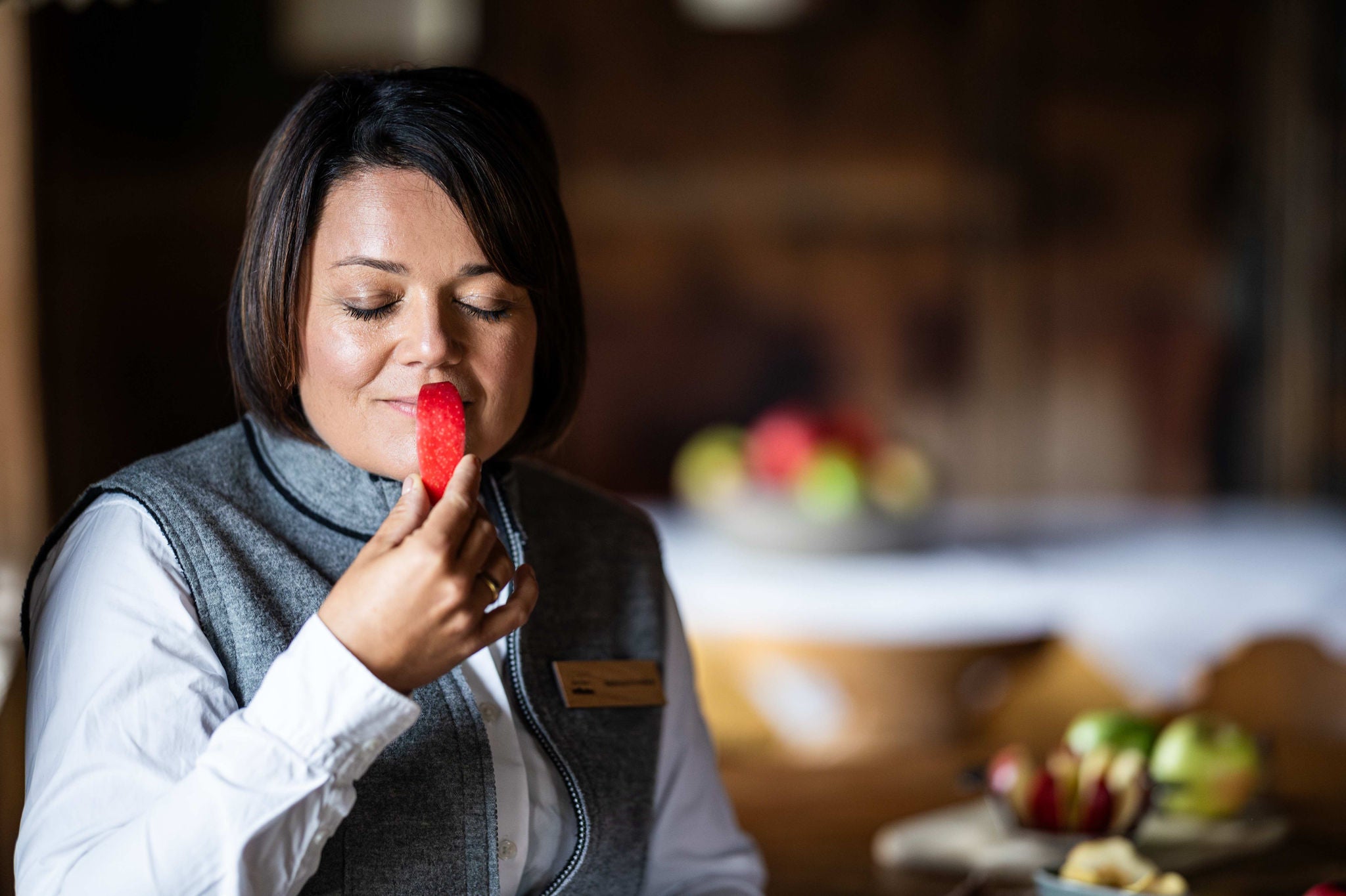 Eine Apfelsommelière riecht an einem Stück rotem Apfel aus Südtirol