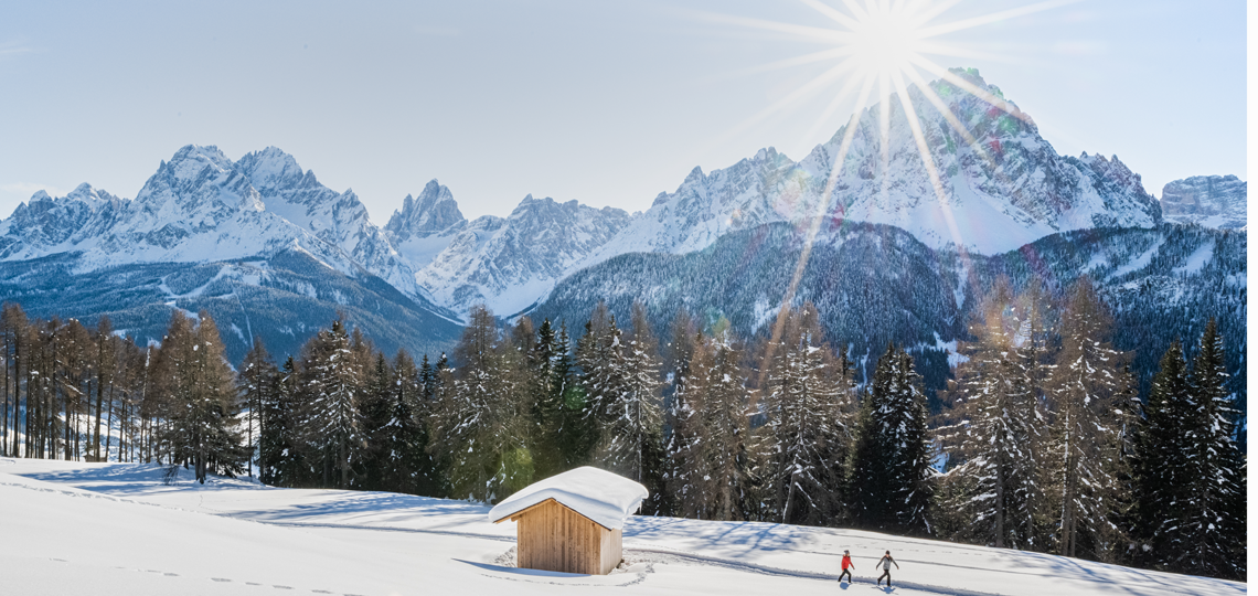 Zwei Personen laufen durch den Schnee bei Sexten im Winter