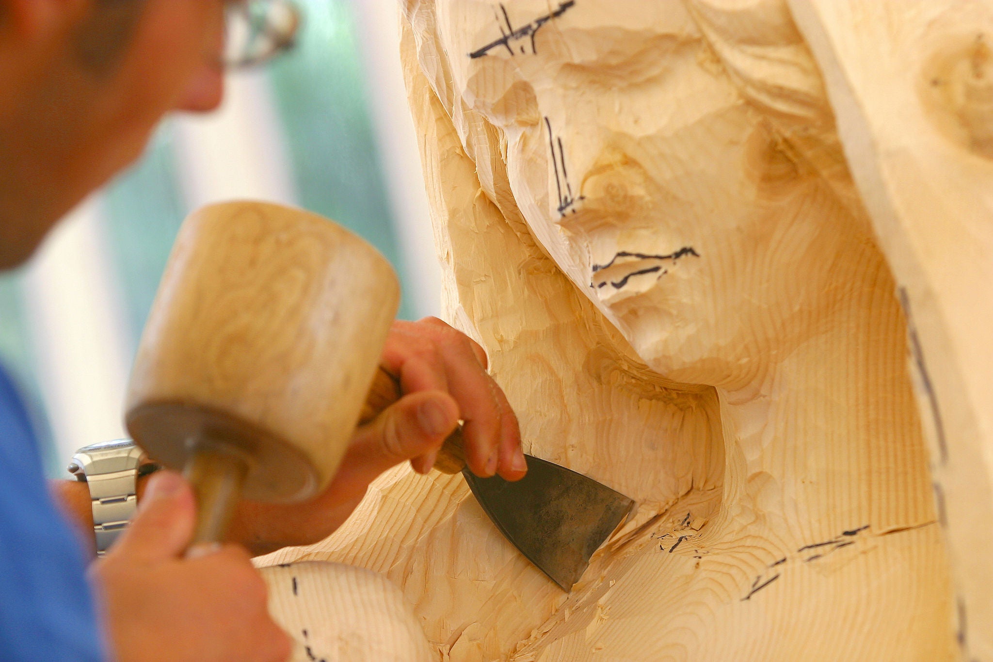 Ein Bildhauer beim Fertigen einer Holzskulptur, die eine junge Frau darstellen soll