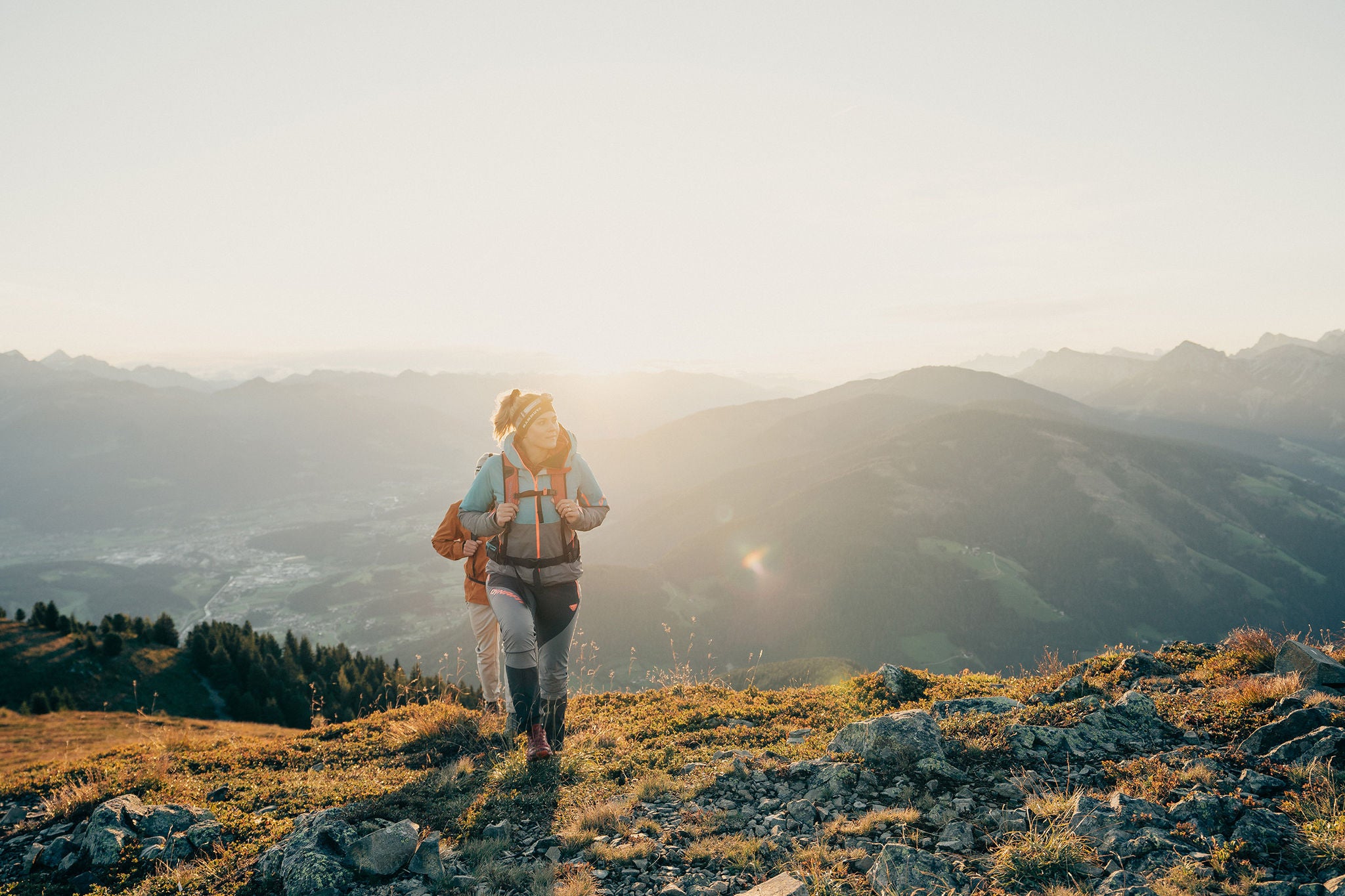 Zwei Personen wandern durch das Eisacktal mit der Sonne im Hintergrund