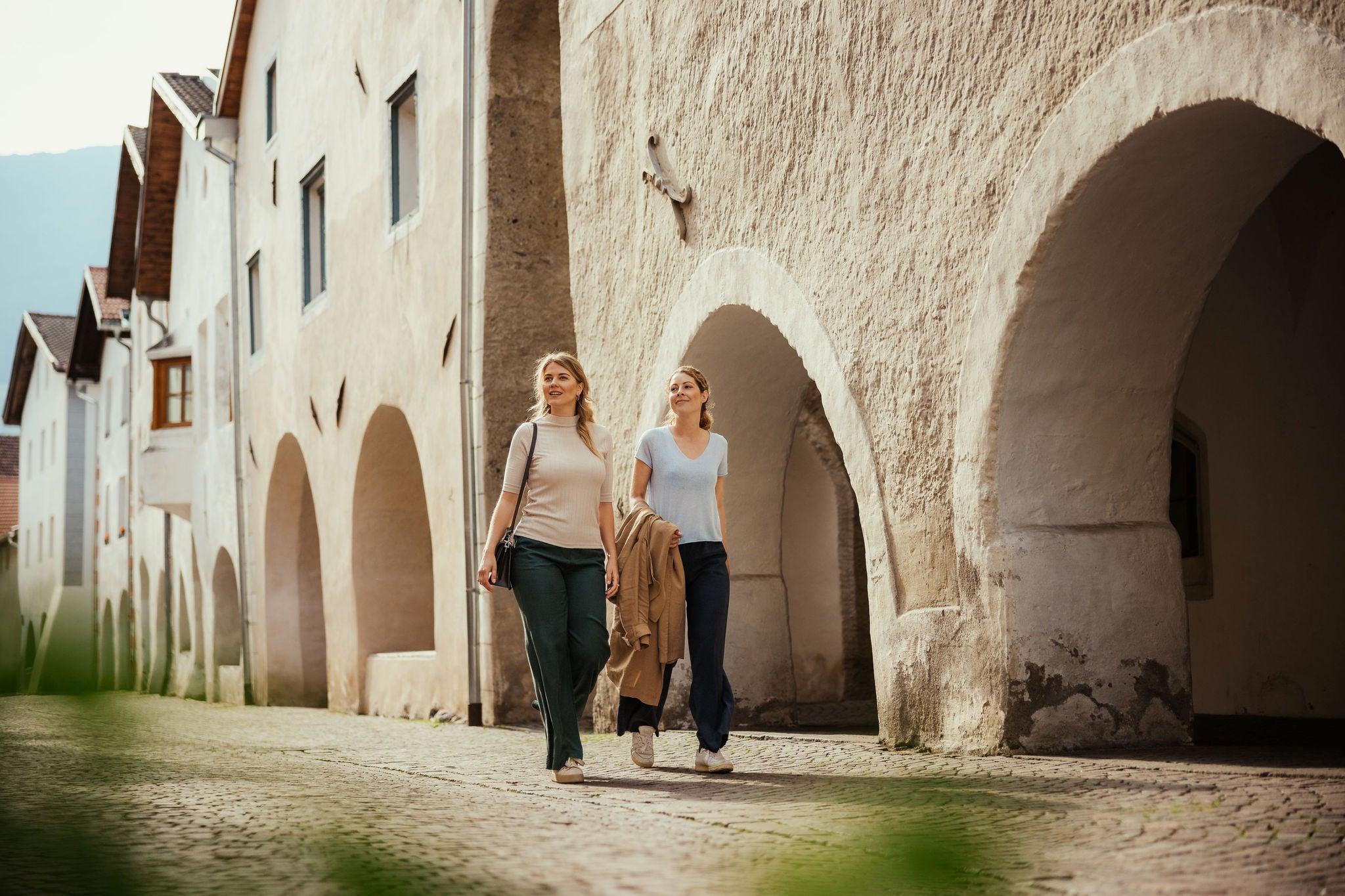 Zwei junge Frauen flanieren durch die historische Laubengasse von Glurns, eine von den Borghi più belli d'Italia.