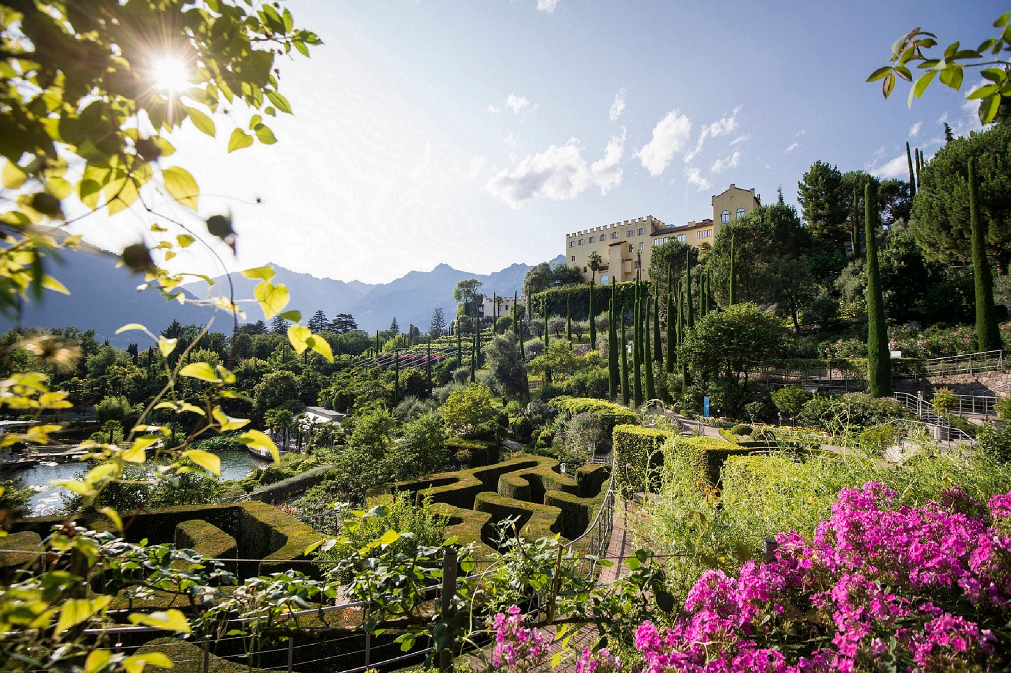 Verschiedene Gartenlandschaften mit Zypressen und einem englischen Garten schmiegen sich an den Schlosshang