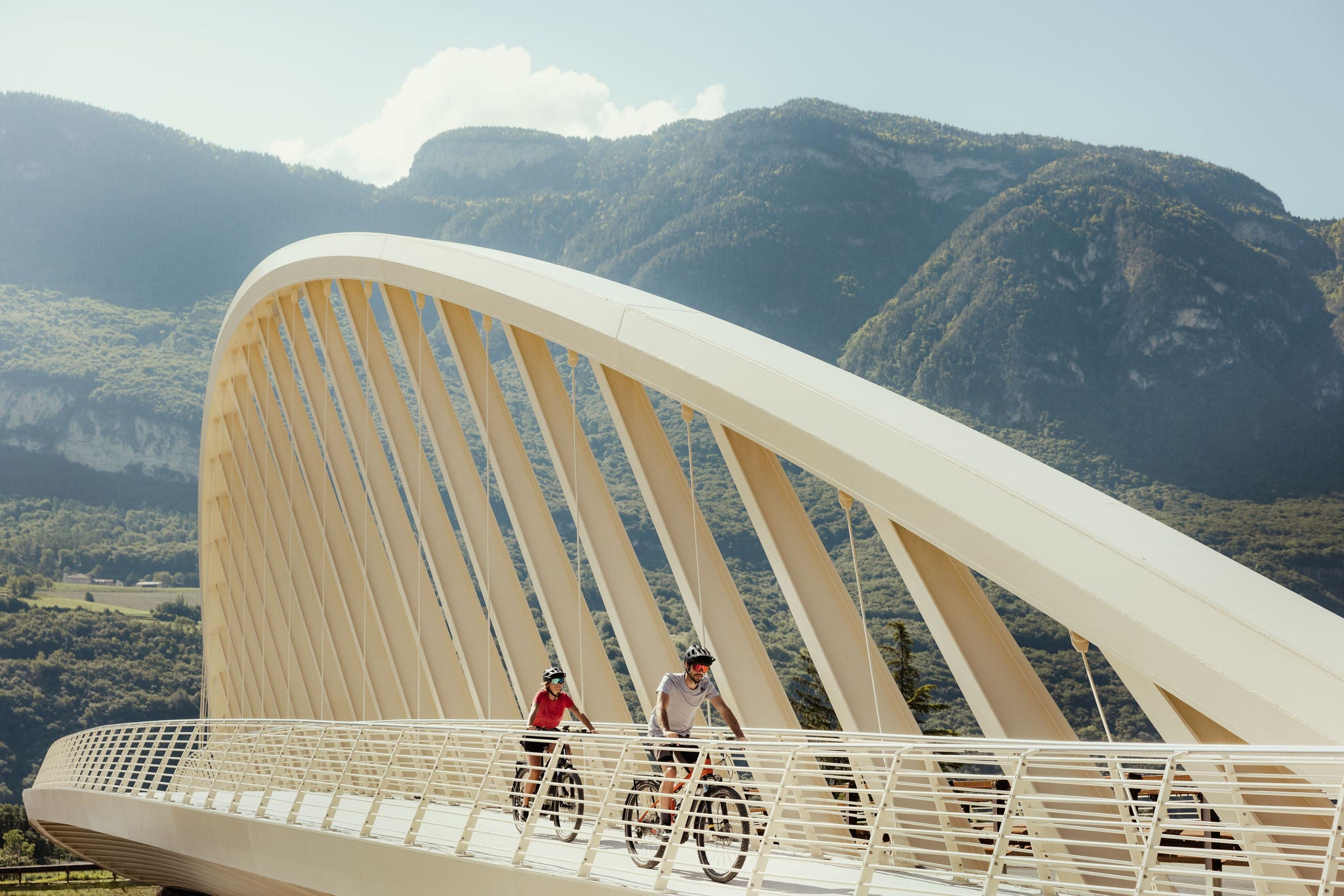 Zwei Radfahrer überqueren die moderne Brücke am Talradweg der Etschradroute