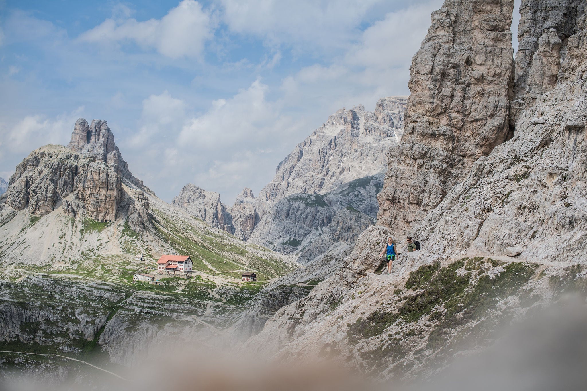 Zwei Wanderer im Hochgebirge der Dolomiten mit Blick auf eine Schutzhütte