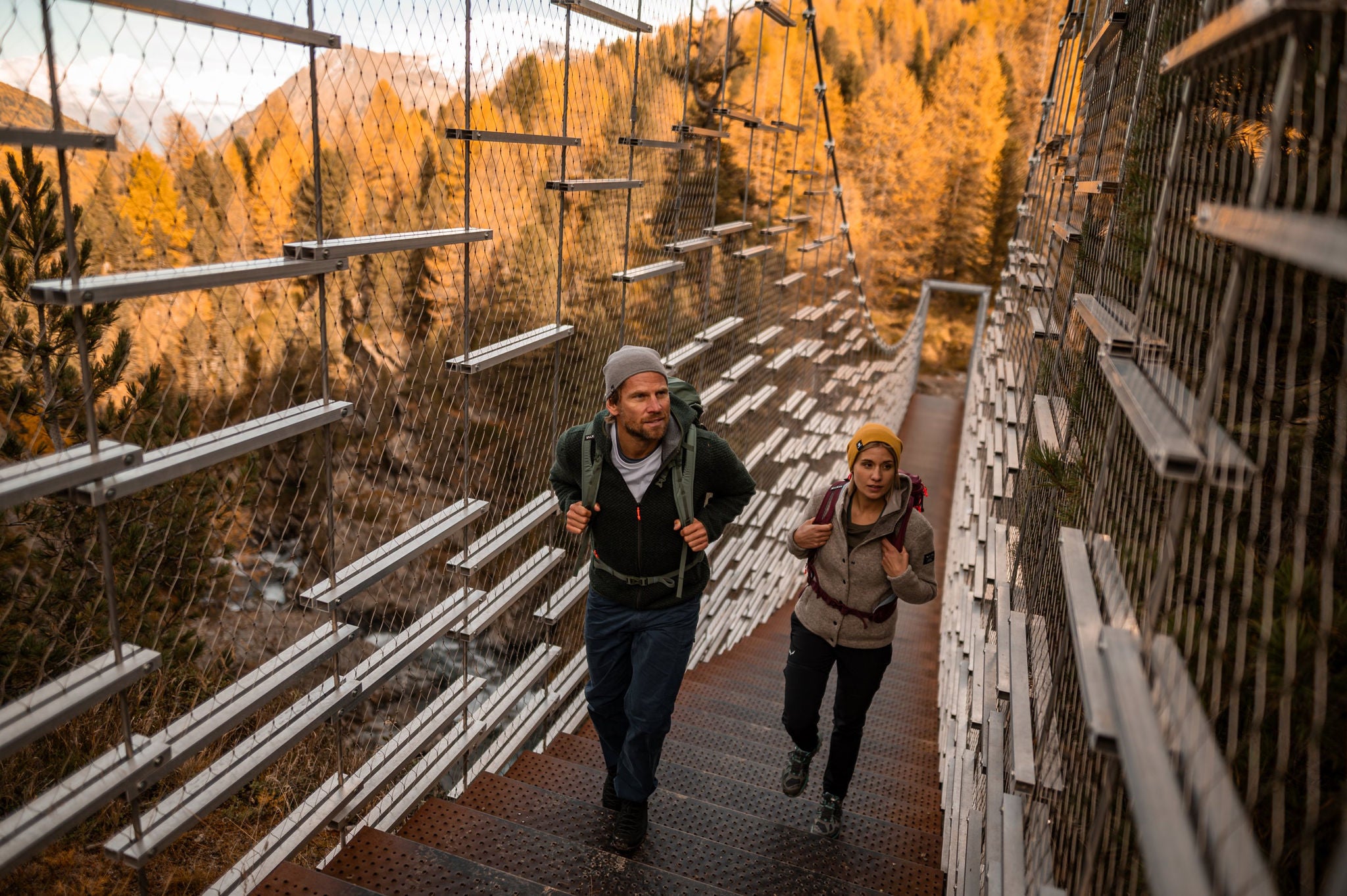 Eine Frau und ein Mann überqueren die Hängebrücke über die Plimaschlucht