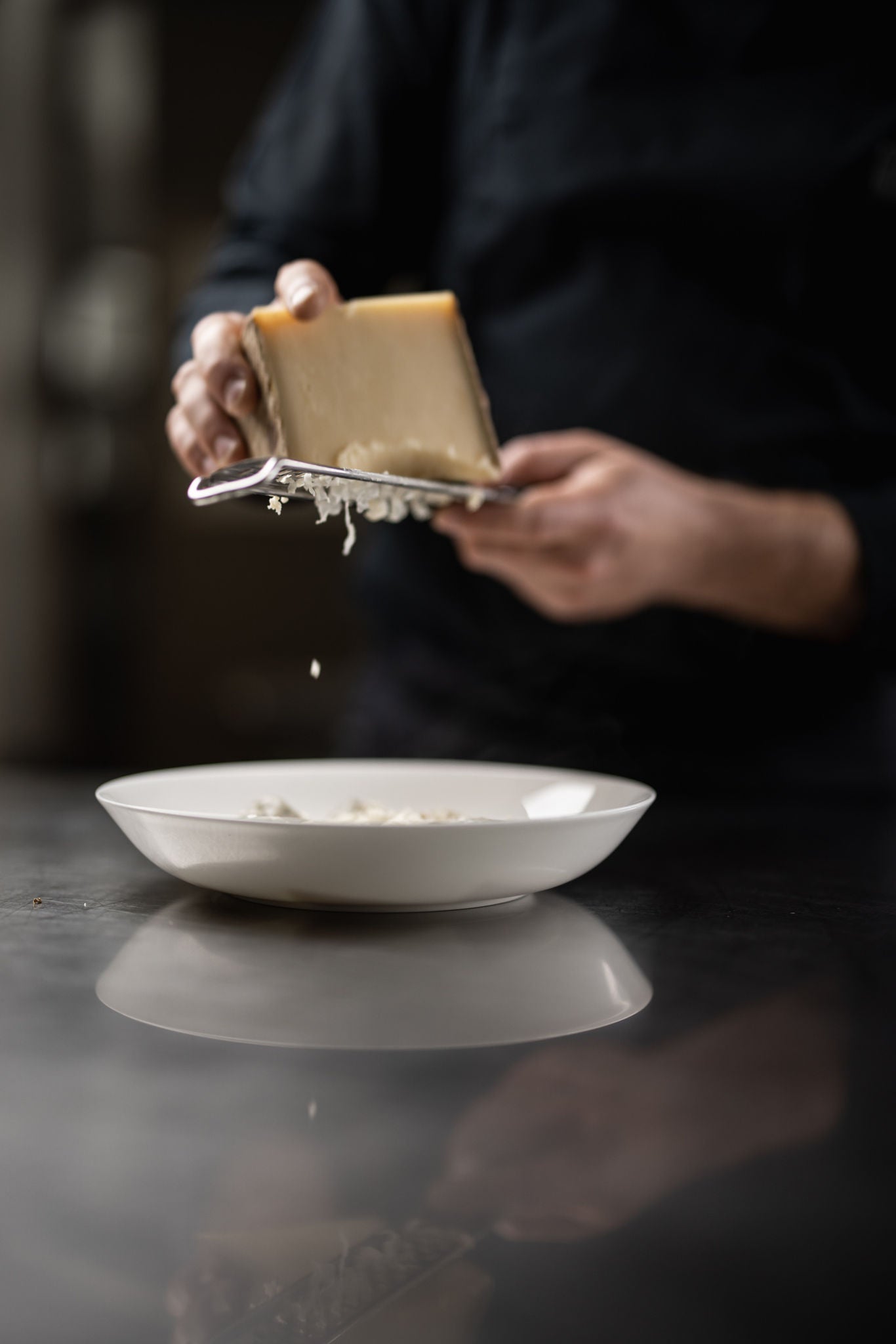 Eine Person reibt ein Stück Käse