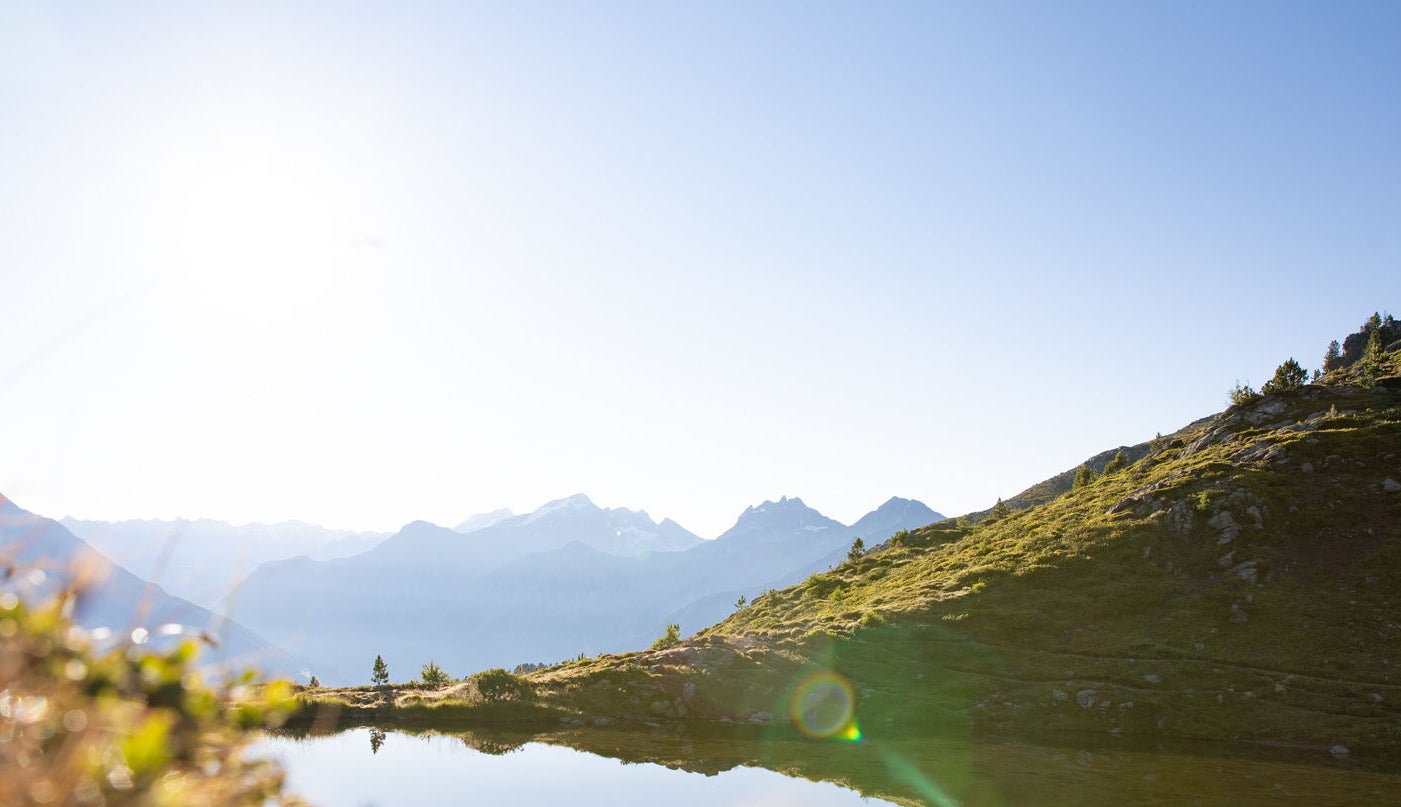 Bergsee mit Bergkulisse unter strahlend blauem Himmel
