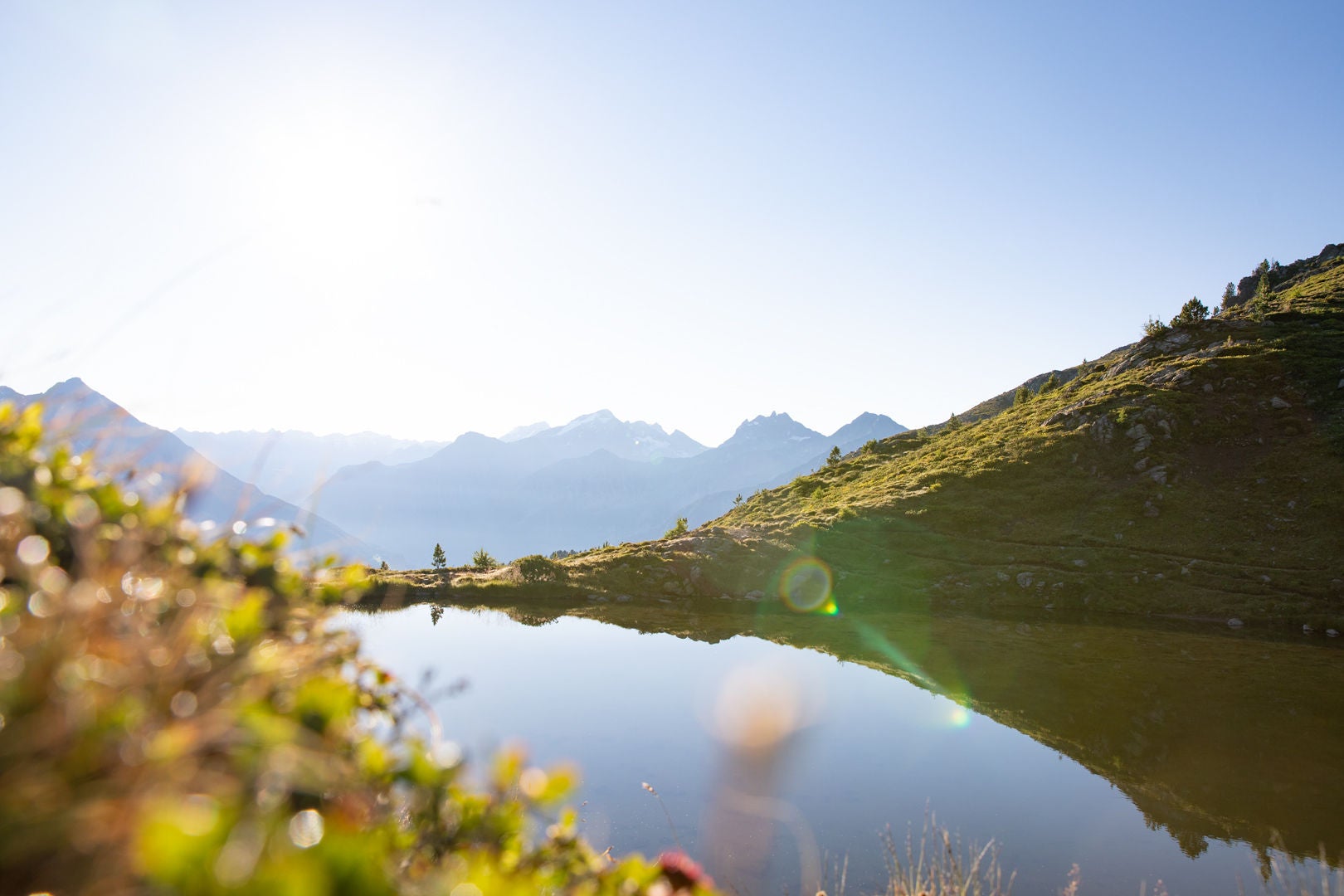 Bergsee mit Bergkulisse unter strahlend blauem Himmel