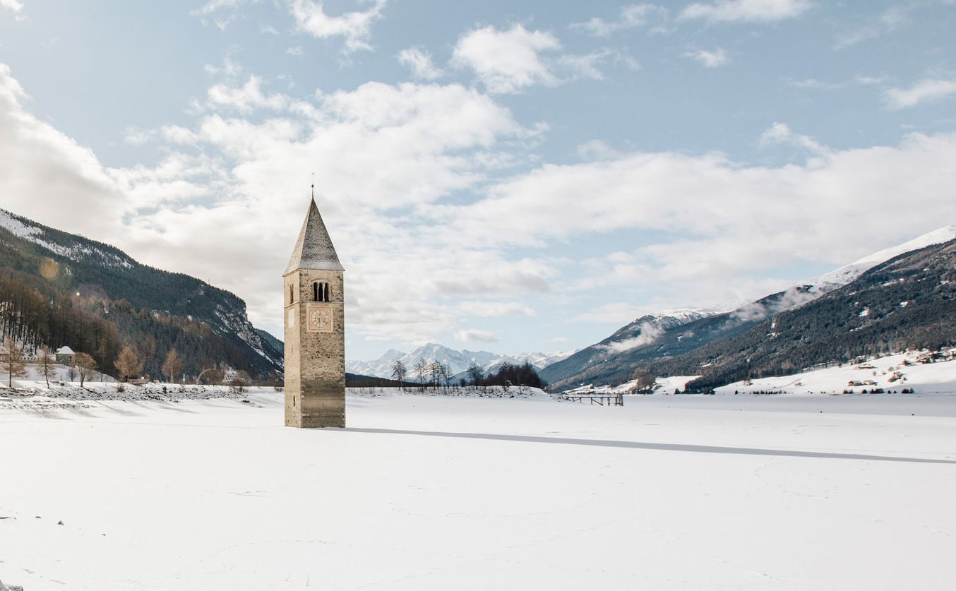 Der zugefrorene Reschensee mit dem heraus ragenden, charakteristischen Kirtchturm.