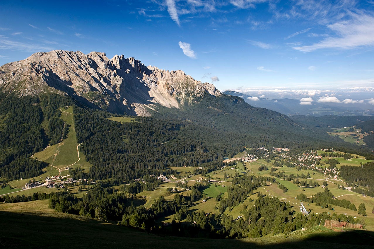 Der Karerpass mit den Gipfeln des Rosengartens und ausgedehnten Wäldern an einem Sommertag.