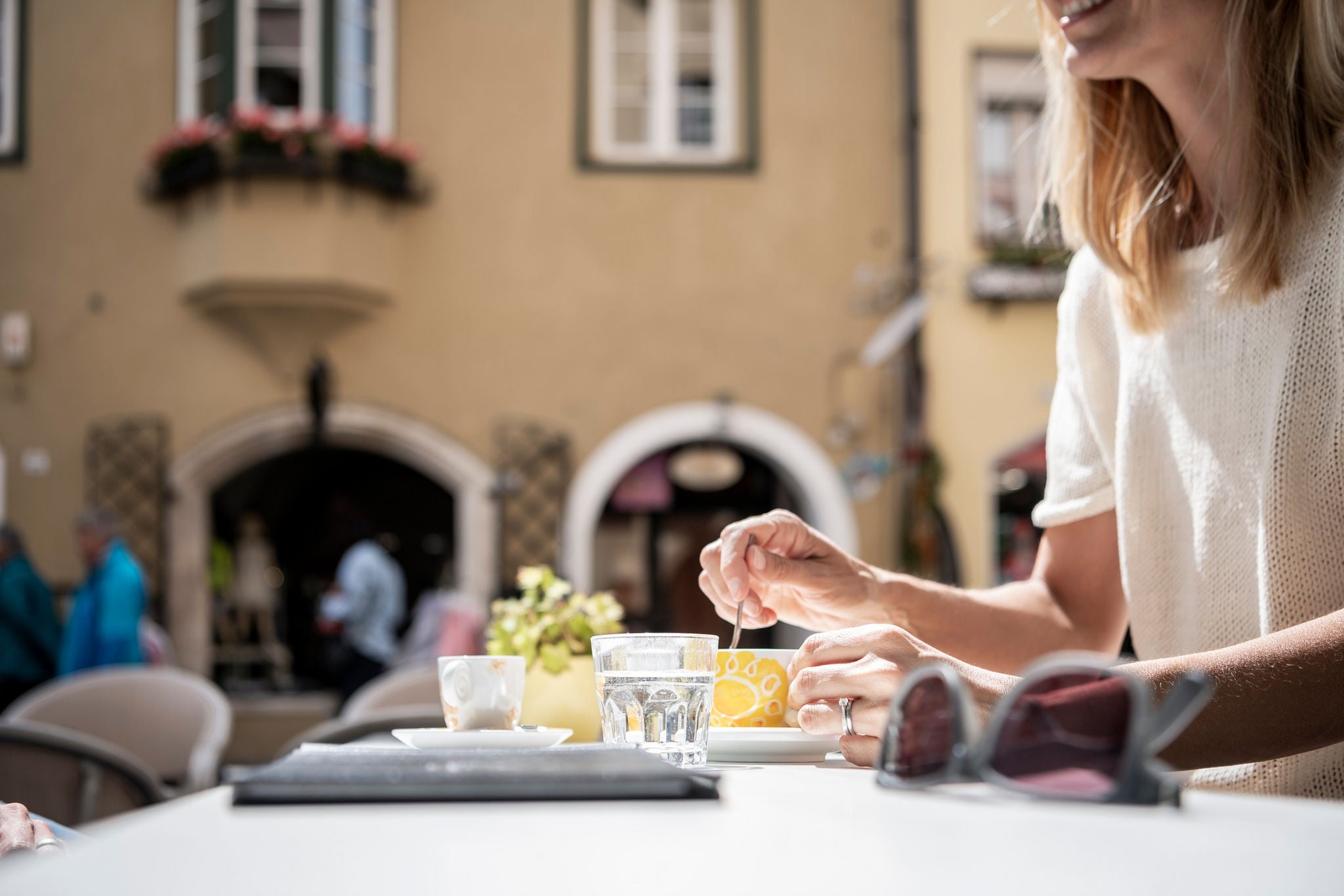 Ein Frau rührt in einer Kaffeetasse beim Besuch eines Straßencafès in der Stadtgasse von Sterzing