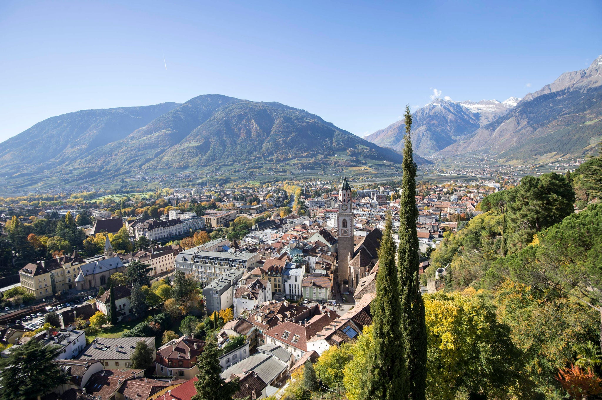 Die Meraner Altstadt an einem strahlenden Herbsttag umrahmt von Zypressen und Berge