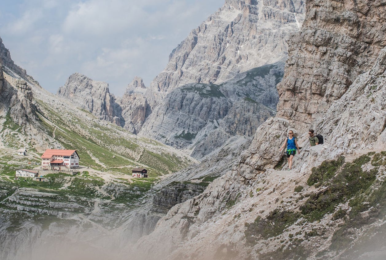 Zwei Wanderer im Hochgebirge der Dolomiten mit Blick auf eine Schutzhütte