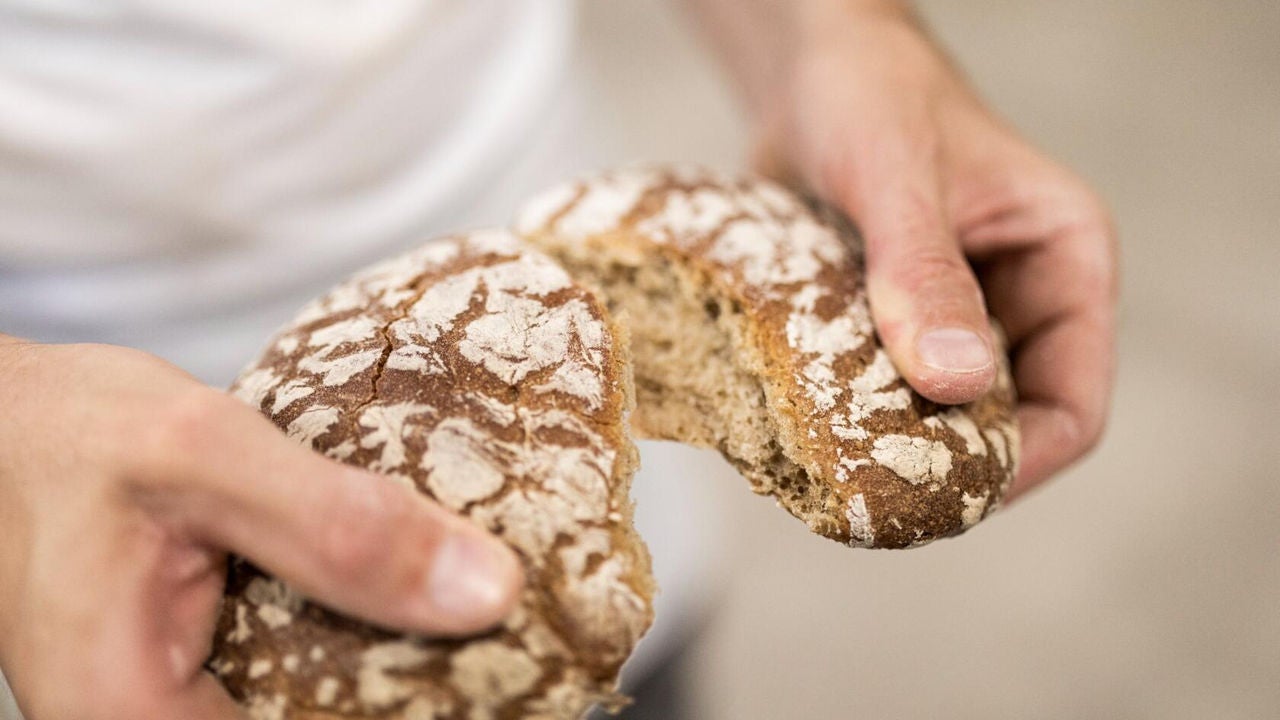 Eine Person teilt einen Laib Südtiroler Brot in zwei