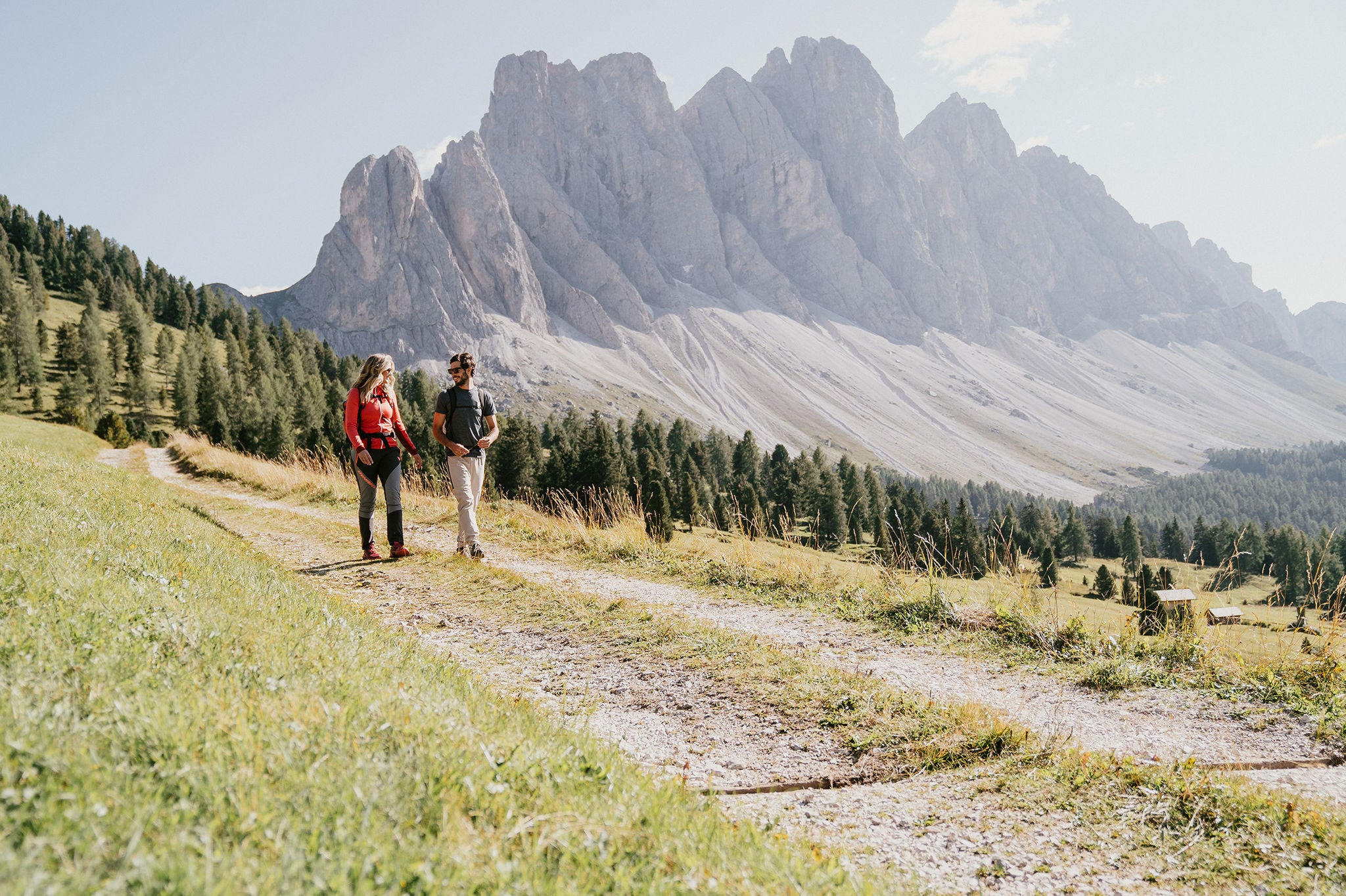 Zwei Personen wandern bei guten Wetter mit dem Villnösser Geisler im Hintergrund