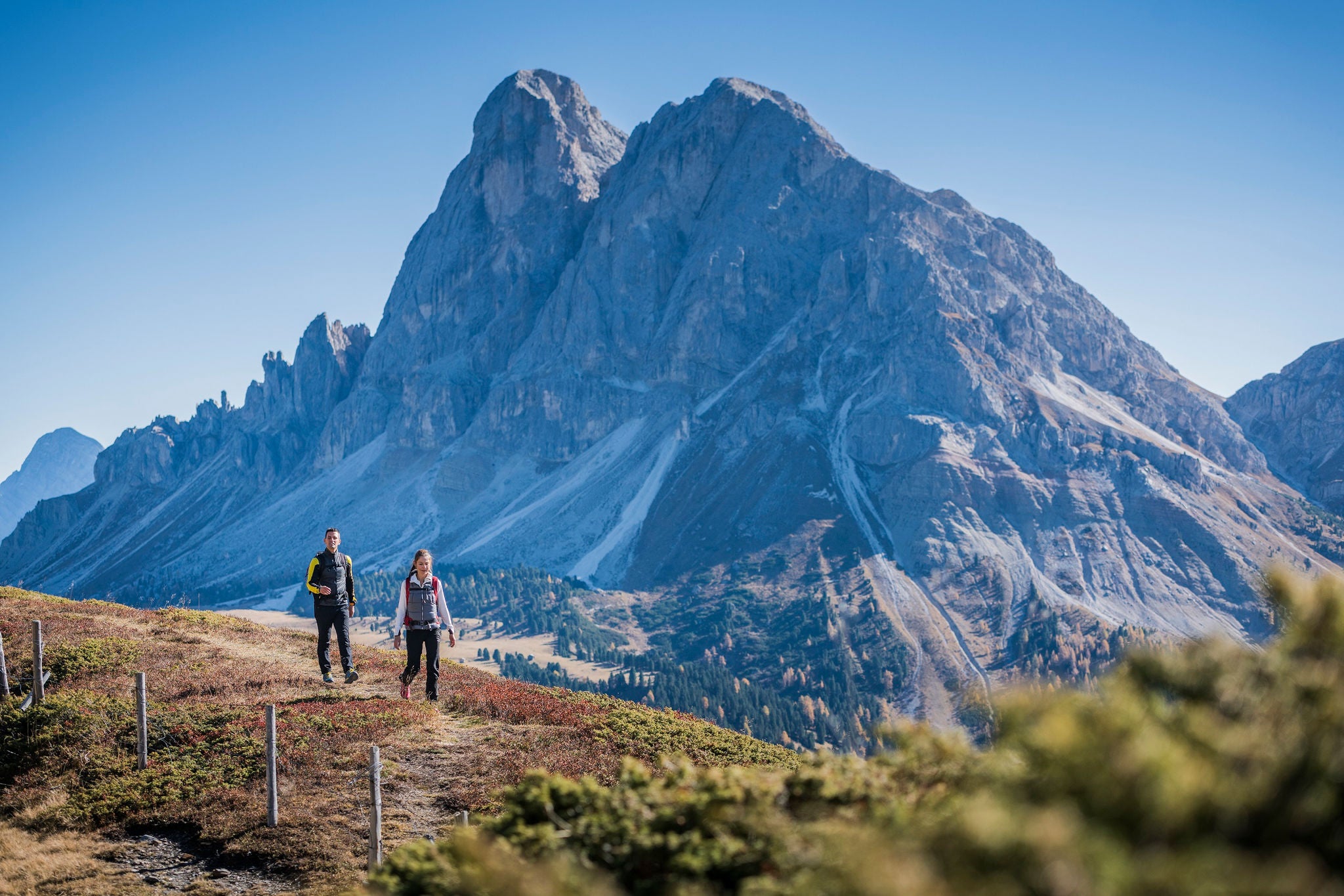 Zwei Menschen wandern im Herbst vor dem Peitlerkofel
