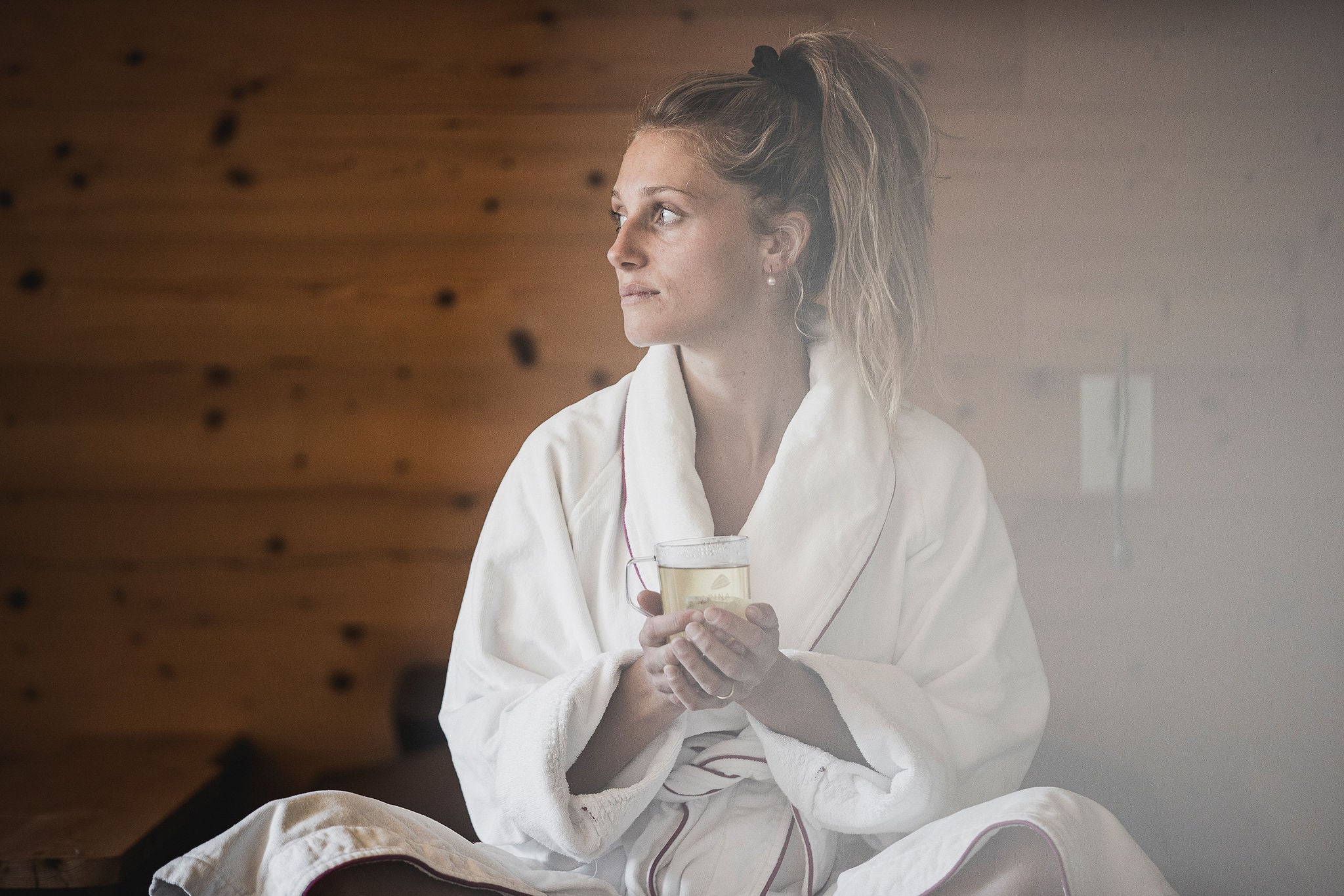 Dame im Bademantel mit Tee in der Hand beim Relaxen im Wellnessbereich