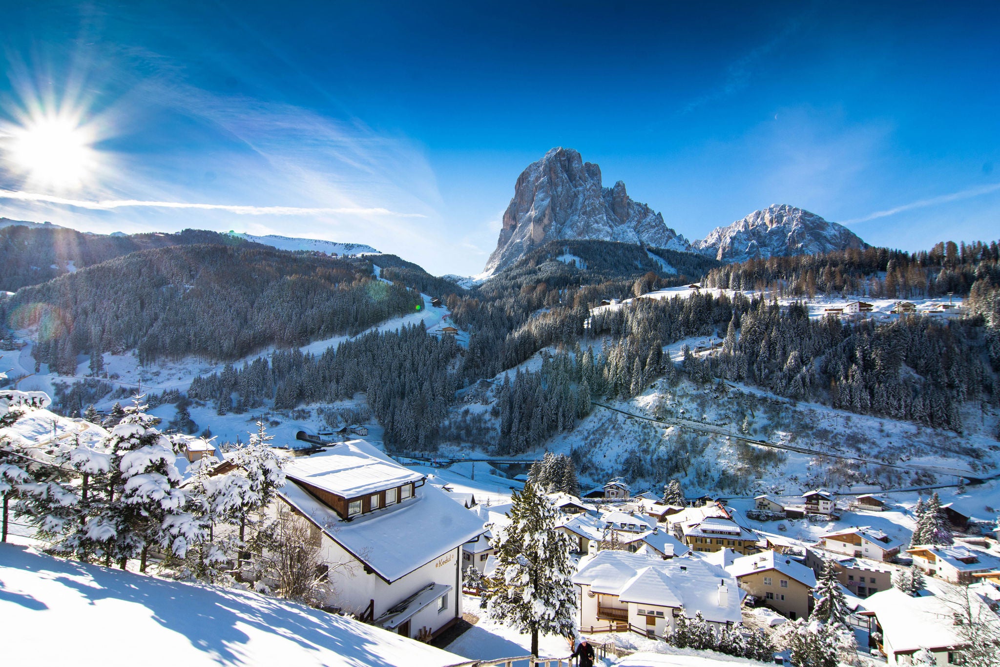 St. Christina im Winter mit der Sonne die Hinten den Bergen zu sehen ist